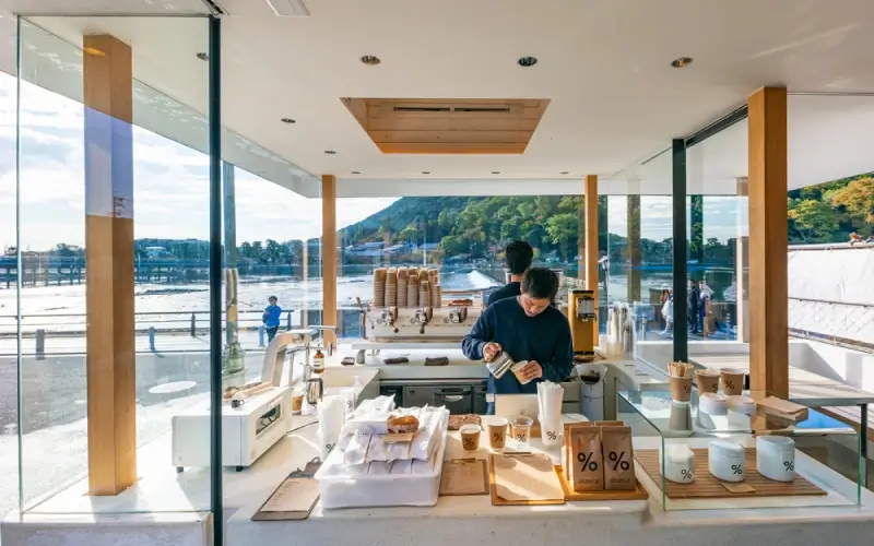 10 ร้านกาแฟญี่ปุ่น 2569 ที่ต้องไปลอง หอมกรุ่นจนต้องบอกต่อ 2 % Arabica Kyoto Arashiyama ร้านกาแฟญี่ปุ่นสไตล์มินิมอลริมแม่น้ำโฮซุ โดดเด่นด้วยวิวภูเขาและบรรยากาศเงียบสงบของเกียวโต